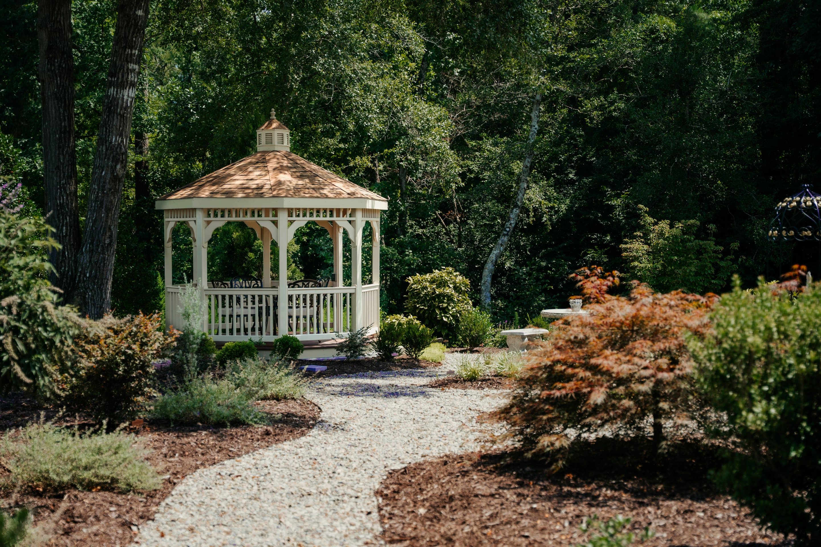 A cream gazebo surrounded by layered garden beds at a finished landscape project.